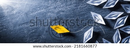 Yellow Paper Boat With Compass Leaving Group And Changing Direction - Entrepreneur - Business Opportunity Royalty-Free Stock Photo #2181660877