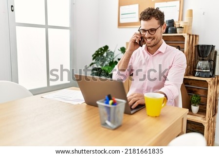 Young hispanic man smiling confident talking on the smartphone at office