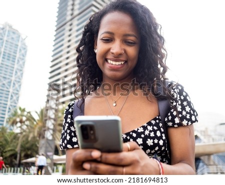  Young african american woman chatting with mobile in the street. Communication, social networks