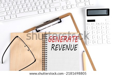 Notebook with the word GENERATE REVENUE with keyboard and calculator on white background