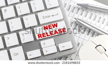 NEW RELEASE text on a keyboard wirh chart and pencil