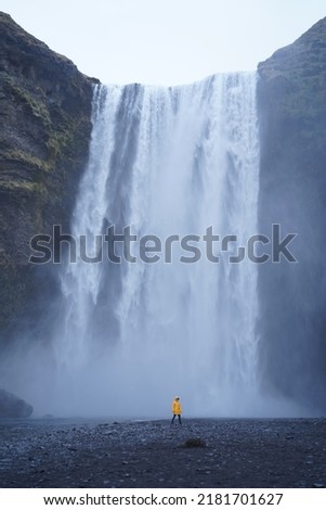 Yellow jacket man with a waterfall behind him