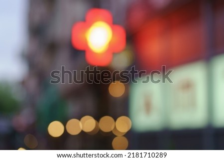 Defocused photography of a red cross, the symbol used for medical intitutions. Symbol is located on the exterior of a building in the Kaliningrad city. Blurred motion in the city