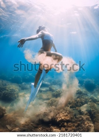 Freediver woman with sand in hands. Lady freediver with fins underwater in blue ocean Royalty-Free Stock Photo #2181720401