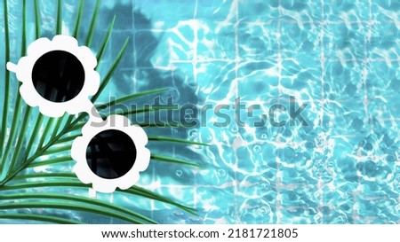 Summer trendy creative idea with white modern sunglasses with palm tree and waves in water on pastel blue background. 80s or 90s retro aesthetic fun idea. Minimal summer fashion idea.