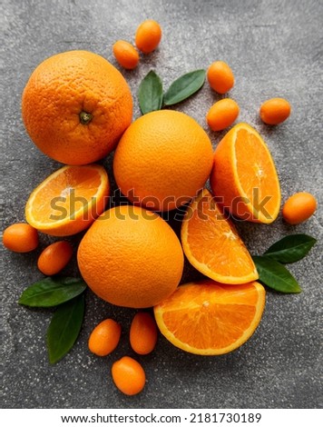 Fresh ripe oranges and  kumquat on dark concrete background