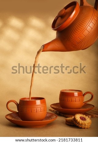 Hand pouring masala tea from a teapot into a glass. Royalty-Free Stock Photo #2181733811
