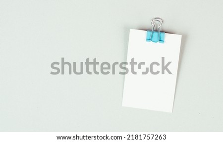 Blank white paper with a paperclip on a gray colored background, copy space for text, reminder or message in the office, communication concept