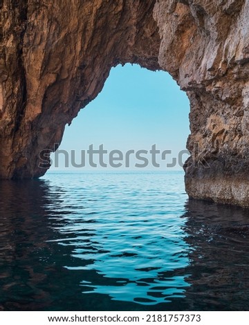 View of blue sky through a natural arch, Blue Grotto, Malta. Royalty-Free Stock Photo #2181757373