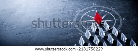 Red Paper Boat On Compass Leading A Fleet Of Small White Boats - Business Leadership Concept Royalty-Free Stock Photo #2181758229