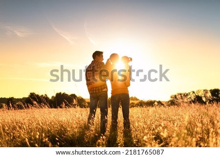 Happy family, mother, father, child  daughter standing in a open field facing nature sunset

