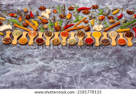 A set of spices on a gray background. Variety of spices from India. Food decoration design. Various spices, peppers and herbs close-up top view. Set of peppers, salt, herbs and spices for cooking. Royalty-Free Stock Photo #2181778133