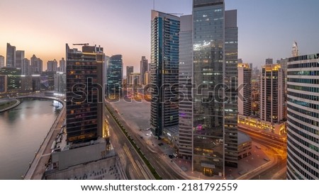 Cityscape of skyscrapers in Dubai Business Bay and downtown with water canal aerial day to night transition. Modern skyline with towers and waterfront after sunset. A center of international business Royalty-Free Stock Photo #2181792559