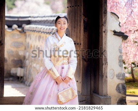 Asian woman traveler in traditional korean dress or hanbok dress walking in old palace with sakura flower background, Seoul city, South Korea Royalty-Free Stock Photo #2181829465