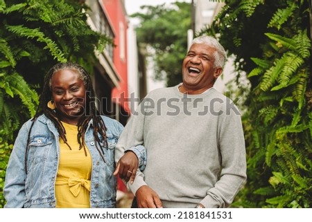 Romantic senior couple laughing cheerfully while walking together outdoors. Happy senior couple spending some quality time together after retirement. Royalty-Free Stock Photo #2181841531