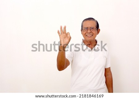 Elderly asian man standing with okay hand gesture. Isolated on white background with copyspace