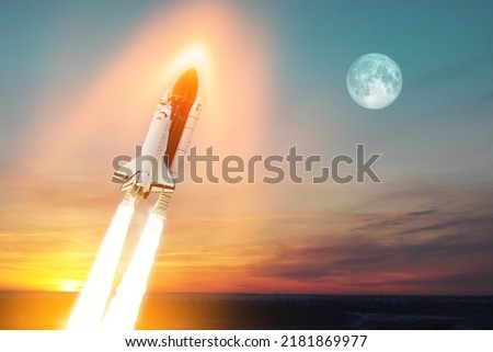 Spaceship lift off. Space shuttle with smoke and blast takes off into space on a background of a sunset with a full moon in the sky. Elements of this image furnished by NASA.