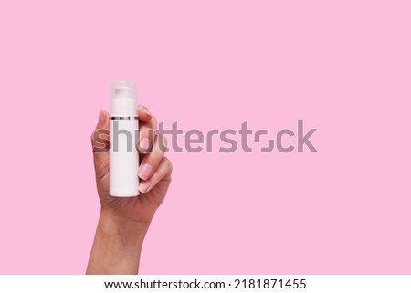 Female hand with cosmetic product in white container mock up on pink color background