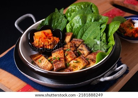 Asian food concept homemade Korean Grilled pork belly BBQ Samgyeopsal-gui with kimchi and shiso and salad on black background with copy space Royalty-Free Stock Photo #2181888249