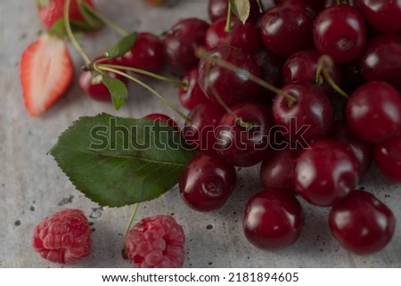 Close - up view to appetizing, fresh, juicy, ripe cherry and raspberry assortment on light gray background