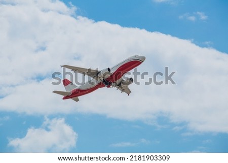 Passenger plane of white-red color flies in the blue sky with white clouds, air transportation concept, population evacuation.
