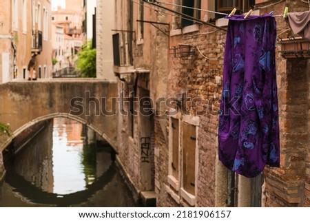 Laundry hung to dry outside over a canal in Venice, Italy and bridge on the background. 