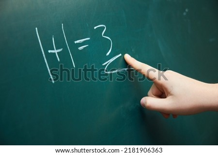A teenager's hand shows an incorrectly solved example on a green blackboard. The concept of education and training.