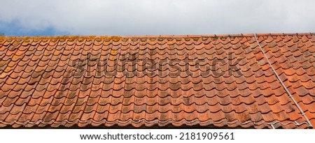 Red clay tiled roof with a cloudy sky in the background. Royalty-Free Stock Photo #2181909561