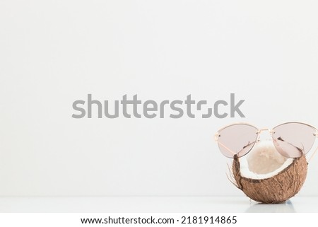 Fresh coconut wearing sunglasses on color background. Hello summer