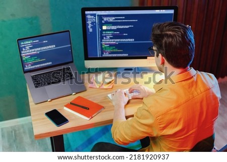 Top back view from above professional young software engineer IT specialist programmer man in shirt work at home writing code on laptop pc desktop computer typing script. Program development concept Royalty-Free Stock Photo #2181920937