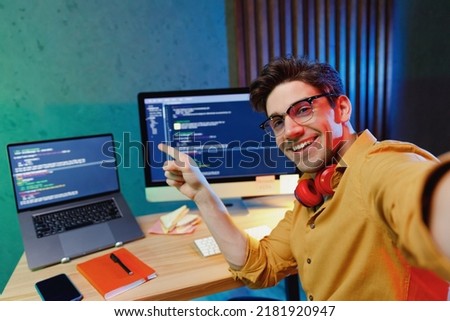 Close up young QA software tester IT engineer programmer man in shirt work at home write code point index finger on laptop pc computer do selfie shot pov on mobile phone Program development concept