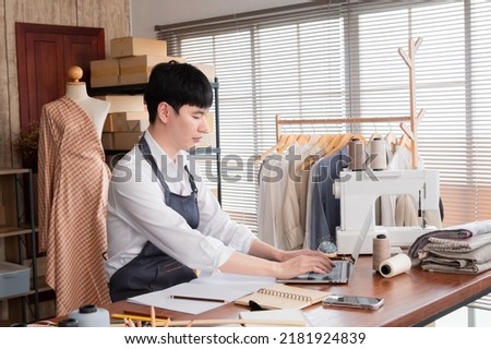 Young LGBTQ Asian Men using laptop Design clothes to sell online, Owners business taking orders online and talking with customer with computer in studio. freelance online marketing concept.