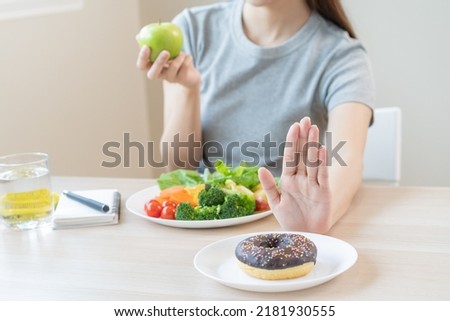 Diet, Dieting asian young woman or girl use hand push out, deny sweet donut and choose green salad vegetables, eat food for good healthy, health when hungry. Close up female weight loss person. Royalty-Free Stock Photo #2181930555