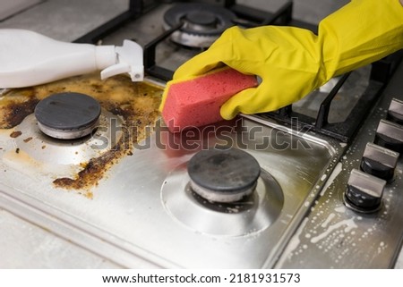 dirty kitchen stove, empty and full bottles of detergents around Royalty-Free Stock Photo #2181931573