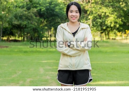 Portrait of young asian woman happy beautiful after exercise in park and  standing with arms folded  looking at camera.
