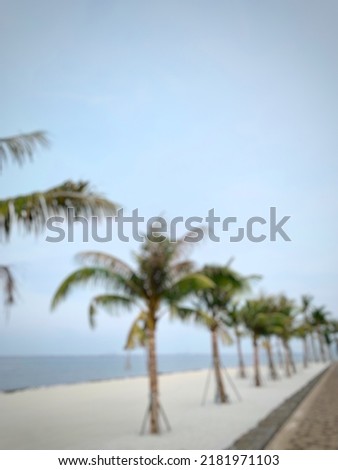 Blurred picture of an empty beach with blue sky, palm trees, white sands, and sidewalk