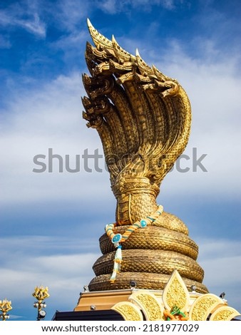 Naga Monument is a bronze seven-headed serpent statue with a total weight of 9 tons, with a total height of about 16.29 meters, enshrined prominently over the banks of the Mekong River, facing north.  Royalty-Free Stock Photo #2181977029
