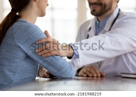 My congratulations. Close up of smiling optimistic doctor gently touching arm of millennial female patient supporting her, informing about good results of lab tests, assuring in complete recovery Royalty-Free Stock Photo #2181988219