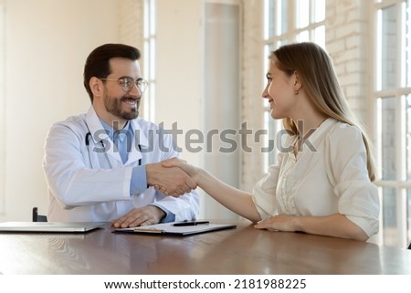 Thank you for help, doctor. Happy grateful young woman patient handshaking with male physician appreciating for good effect of treatment, satisfied with better health state, signing insurance policy
