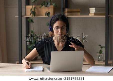 Close up woman in headphones and glasses leading online lesson, using laptop, taking notes, studying, teacher coach explaining, smiling businesswoman consulting client, involved in internet meeting