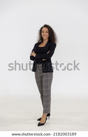 Portrait of smart caucasian businesswoman with curly hair in black jacket suite with trousers smiling arm crossed isolate on white background, vertical full body studio shot