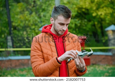 A man operates a drone and repairs it. A guy in an orange jacket shoots a video with a drone, drone repairs and aerial photography close up
