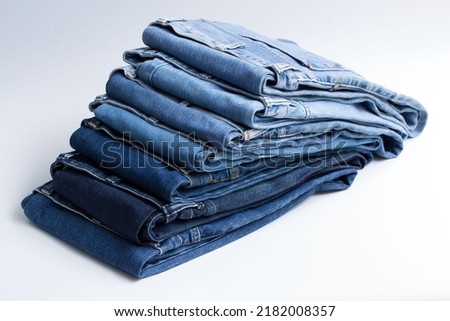 Jeans trousers stack on white background in supermarket and store. business jeans concept. Royalty-Free Stock Photo #2182008357