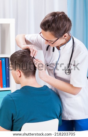 Doctor inspecting skin of head of man