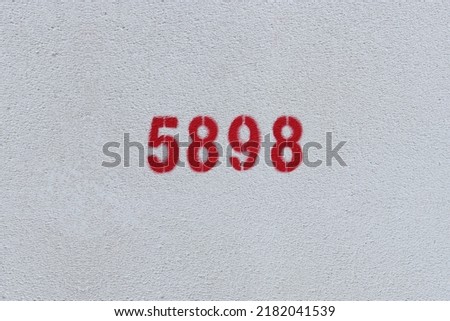 Red Number 5898 on the white wall. Spray paint.

