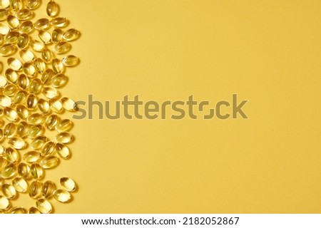 transparent capsules with omega on a yellow background on the left side of the picture. dietary supplements, vitamins. copyspace