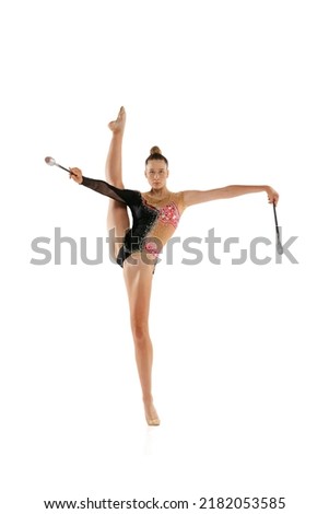 Studio shot of young flexible woman, rhythmic gymnastics artist performing with clubs isolated on white background. Concept of sport, action, ad, aspiration, education, active lifestyle