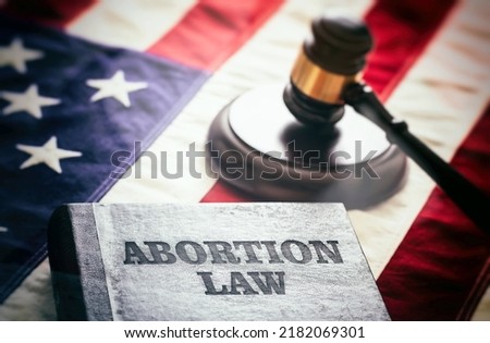 Abortion law in USA concept. Pregnancy termination ban. Judge gavel and Abortion Law book on US flag, close up view  Royalty-Free Stock Photo #2182069301