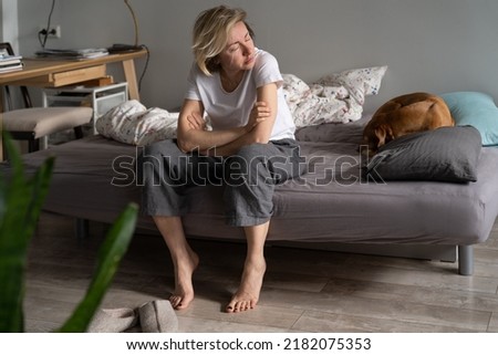 Lonely at 40. Sad single woman feel depressed while living alone, sitting on sofa with dog looking aside, thinking of life purpose, experiencing emotional pain after break up. Loneliness, depression Royalty-Free Stock Photo #2182075353