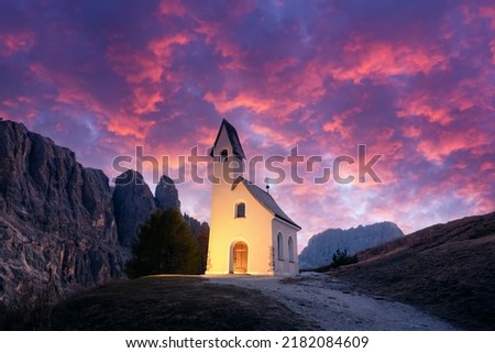 Incredible view on small iIlluminated chapel - Kapelle Ciapela on Gardena Pass, Italian Dolomites mountains. Colorful sunset in Dolomite Alps, Italy. Landscape photography